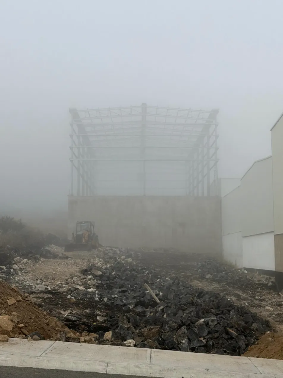 Estructura metálica de una nave industrial entre la niebla